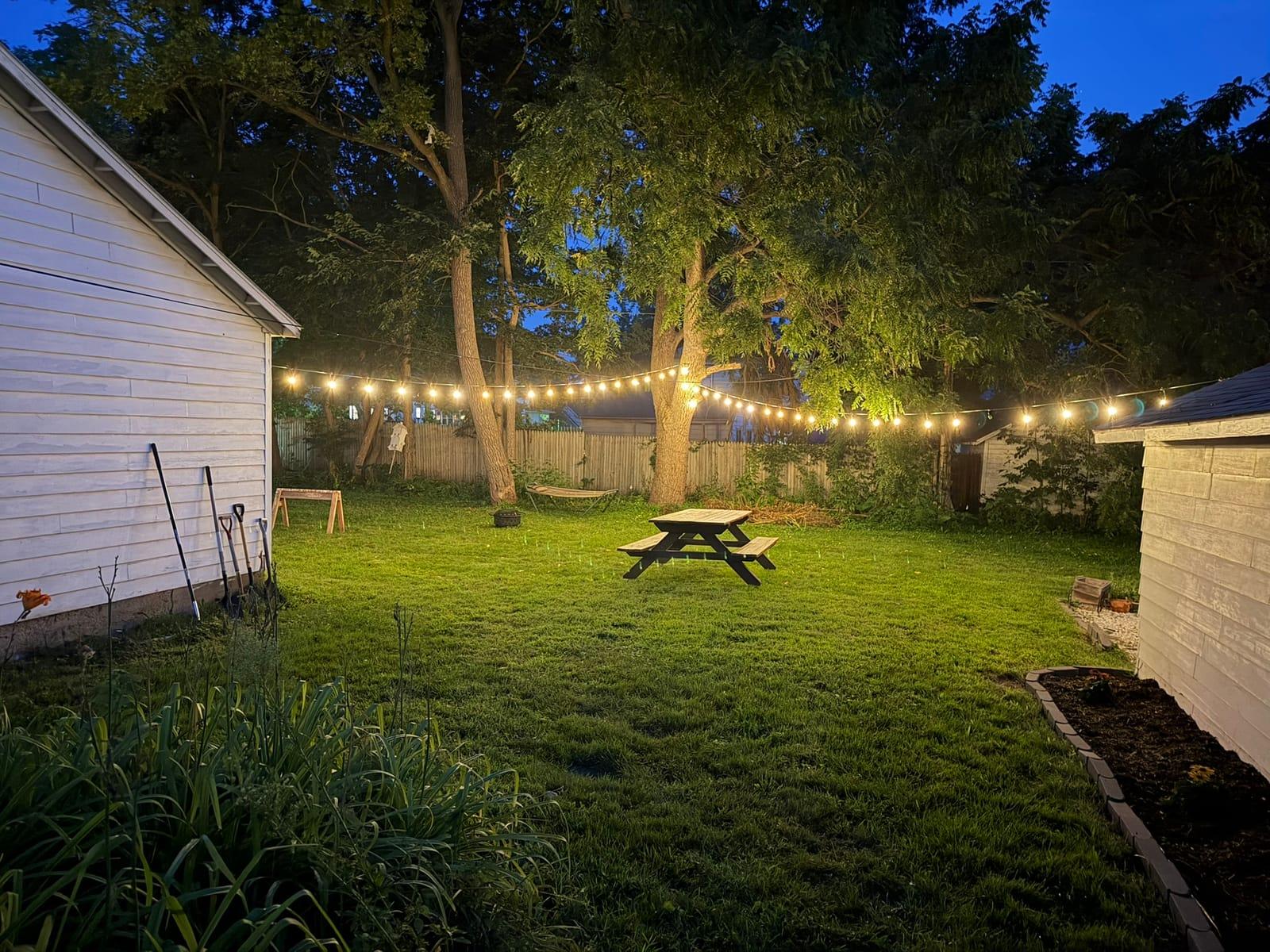 A Rose’s Village backyard on Center Street with string lights at dusk